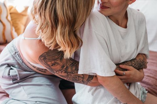 Free A tender moment between a tattooed couple exchanging a gentle embrace indoors. Stock Photo