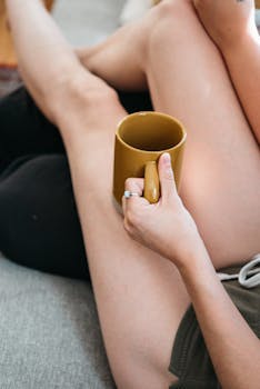 A person holds a yellow coffee mug while lounging indoors, capturing a peaceful moment.