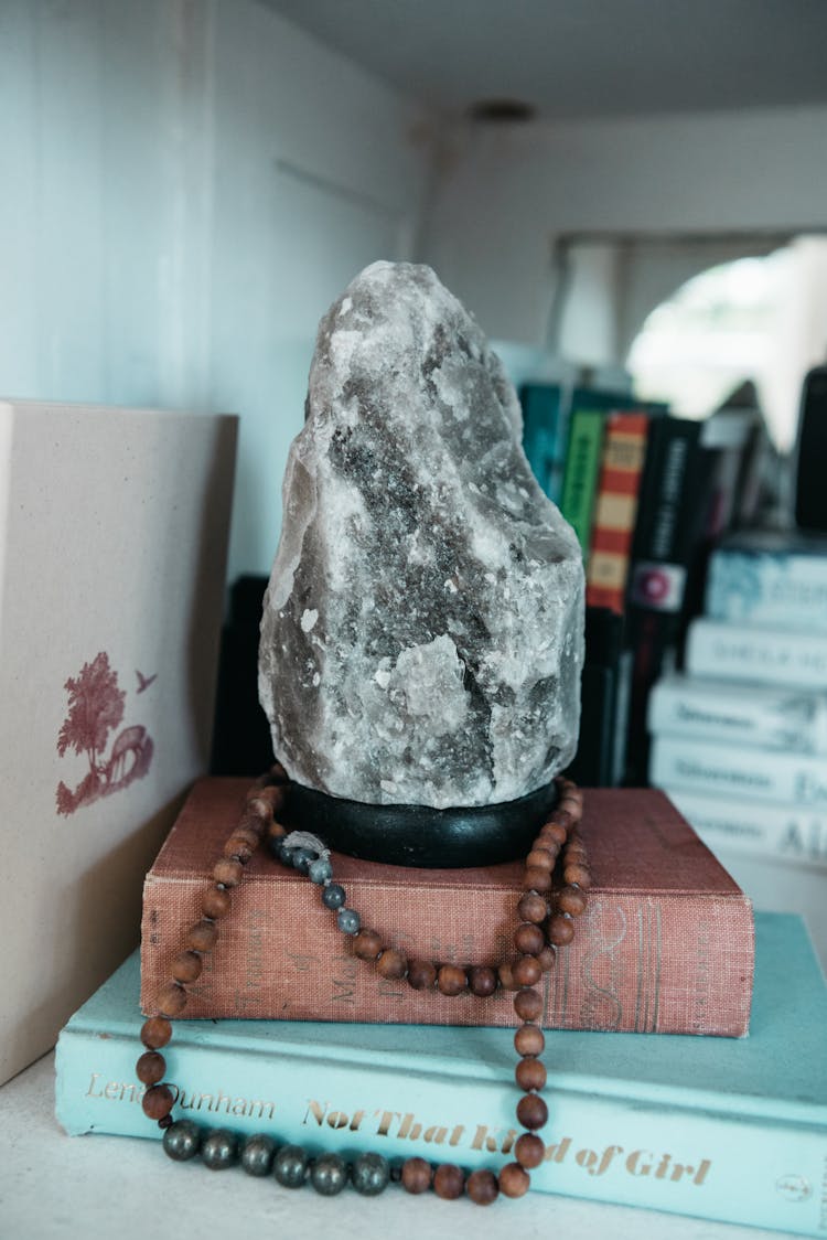 Himalayan Salt Lamp And Prayer Beads On Top Of Books