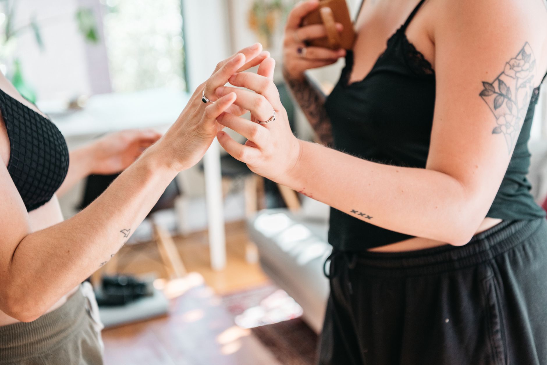 Close-up of two women holding hands, symbolizing love and connection in a bright indoor setting.