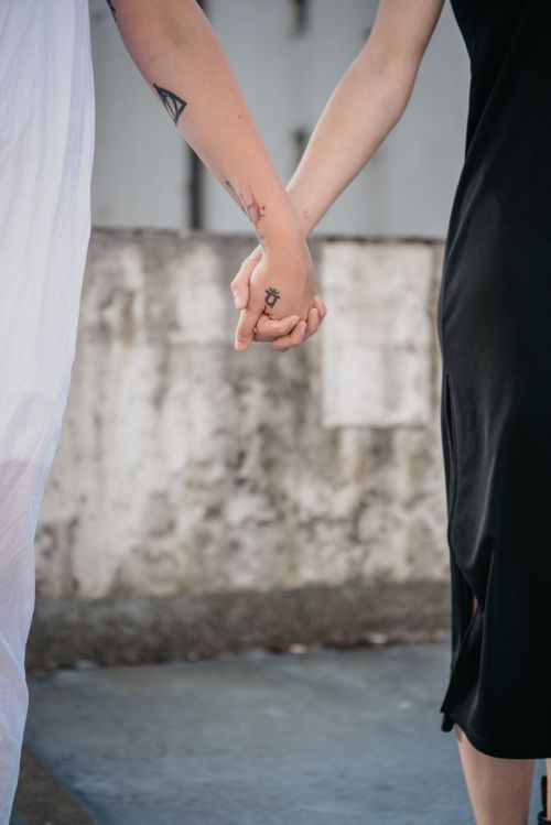 Free A close-up shot of two people holding hands, showcasing tattoos and intimate connection. Stock Photo