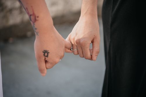 Free A close-up of a couple holding hands, displaying tattoos and wearing rings, symbolizing connection and intimacy. Stock Photo