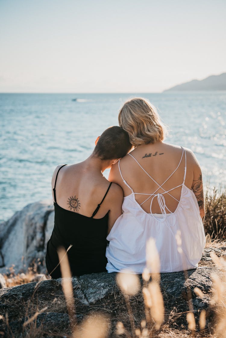 A Romantic Couple Sitting On A Rock Near The Beach