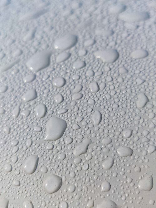 Free A close-up view of water droplets on a white surface with clear textures and reflections. Stock Photo