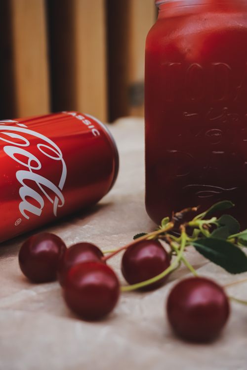Free A vibrant shot of cherries, a Coca-Cola can, and a red drink in a jar creating a refreshing vibe. Stock Photo