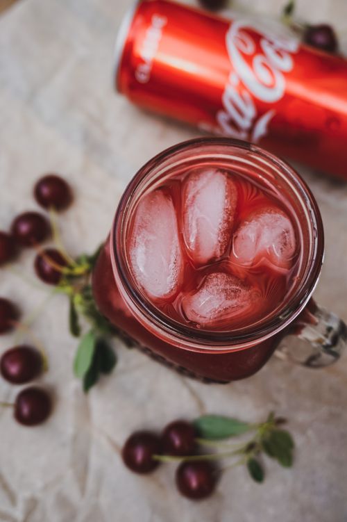 Free Chilled cherry cola drink with ice cubes in a glass mug on a rustic table, perfect for a refreshing treat. Stock Photo
