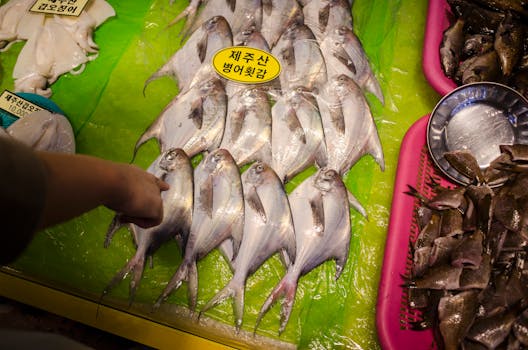 Hands selecting fresh fish at a vibrant market stall, emphasizing freshness and choice.