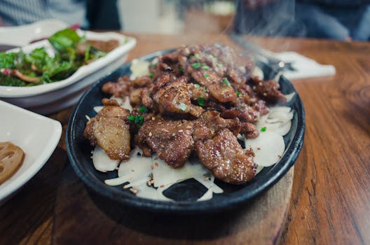 Delicious grilled beef served on a sizzling plate with onions, garnished with greens.