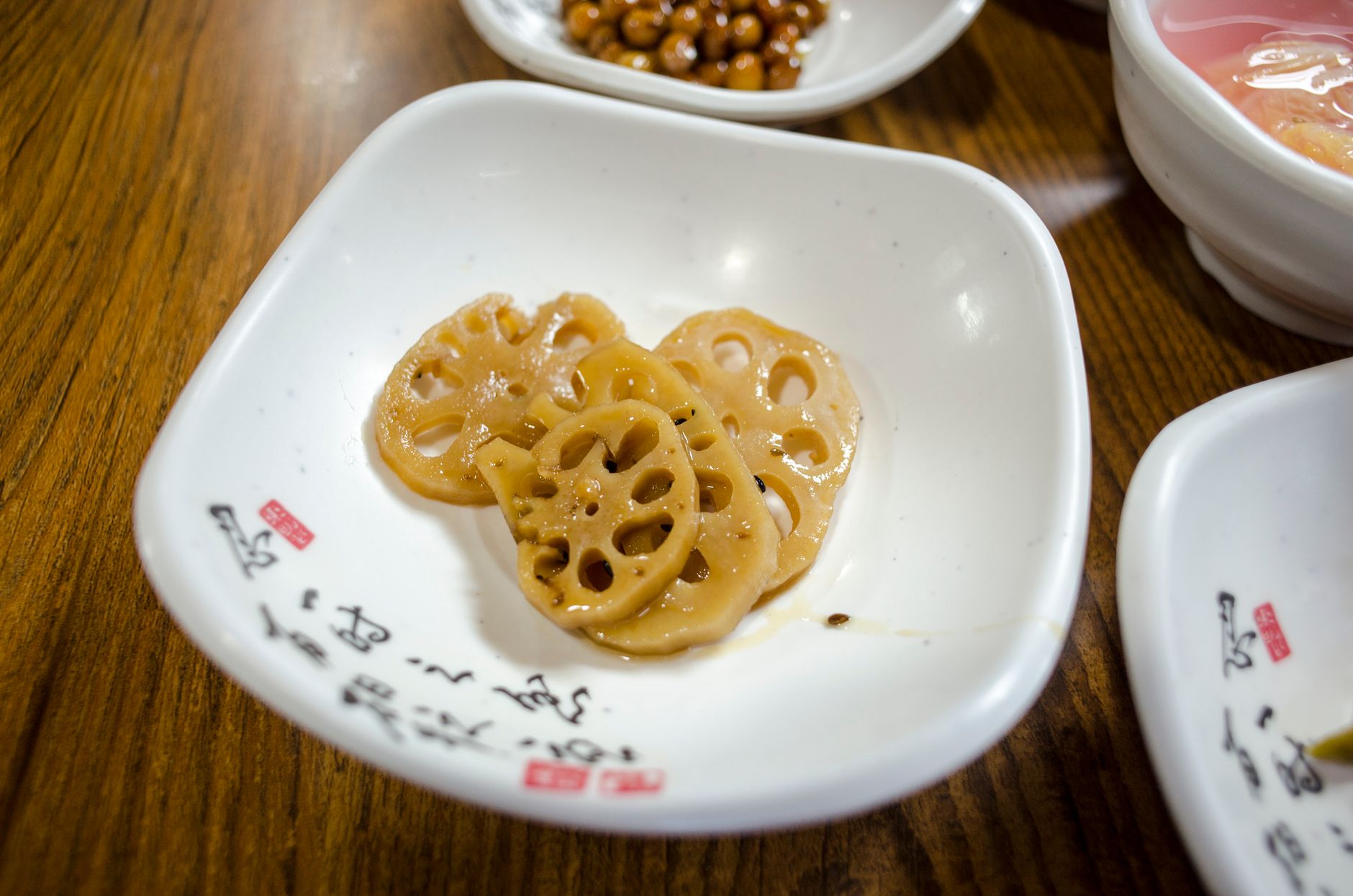 Close-up of sliced lotus root in a dish, a staple in Asian cuisine, presented on a wooden table.