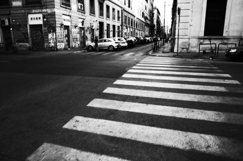 Free Black and white photo of a city street featuring a zebra crossing and row of parked cars. Stock Photo