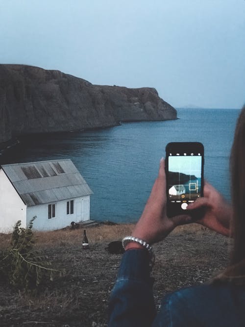 Person Taking Photo of a Building Near Body of Water
