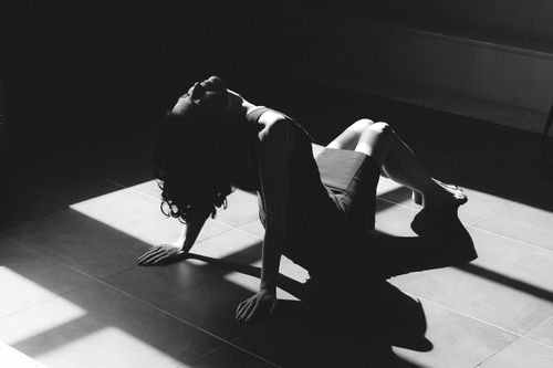 Free Artistic black and white photo of a woman sitting on the floor, highlighting dramatic shadows. Stock Photo