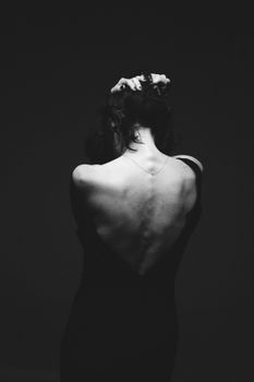 Artistic black and white portrait showing the back of a woman in a contemplative pose.