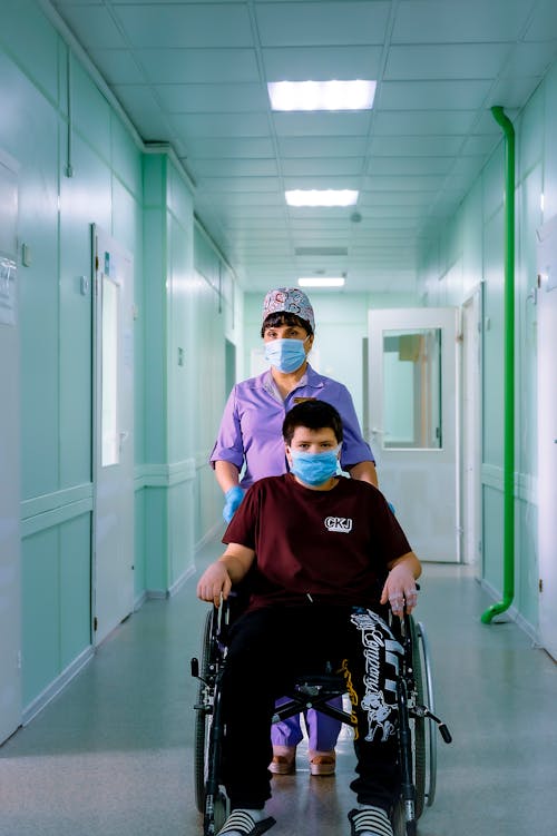 Free Woman Pushing the Boy in Wheelchair Stock Photo
