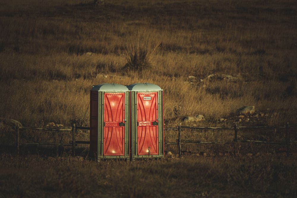 Portable restrooms set up for an outdoor event in a grass field