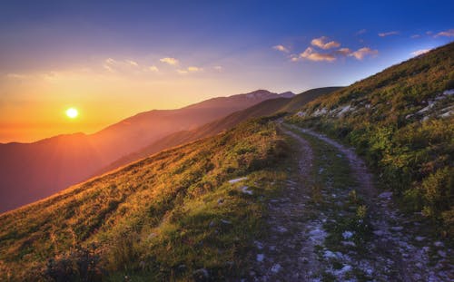 Dirt Road on Mountainside During Sunset