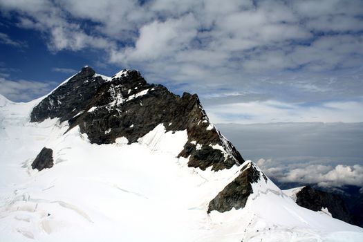 在明亮的蓝天下，白雪皑皑的山峰呈现出壮丽的景色