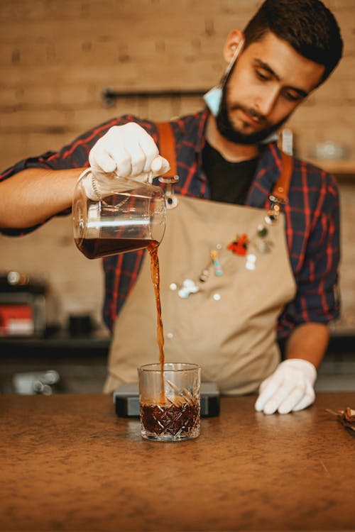 Man Wearing Apron Pouring Coffee on a Glass Mug