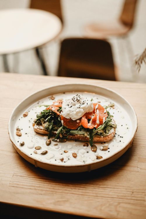 Free Delicious salmon and avocado toast topped with poached egg and seeds, served on a rustic plate. Stock Photo