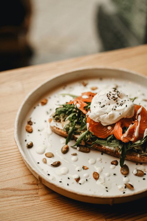 Free Delicious salmon toast topped with a poached egg and arugula, perfect for a healthy meal. Stock Photo
