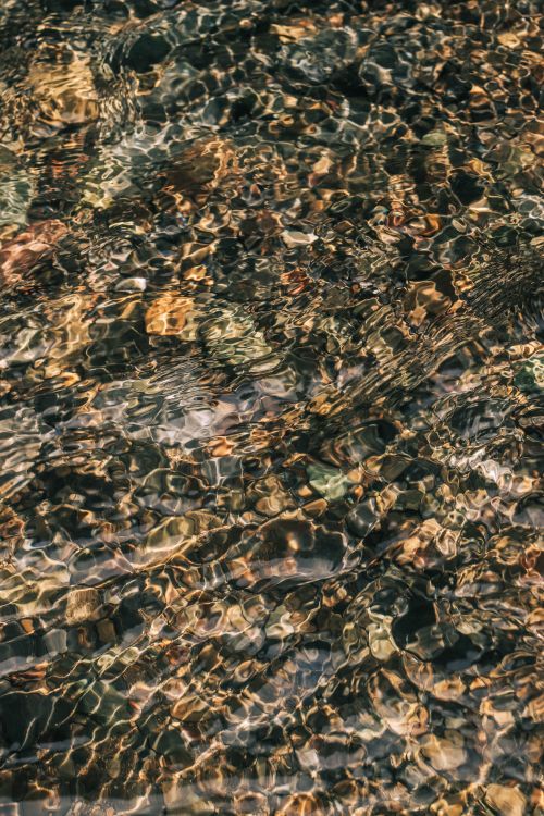 Free Artistic shot capturing the patterns and reflections on a rippled water surface, creating an abstract effect. Stock Photo