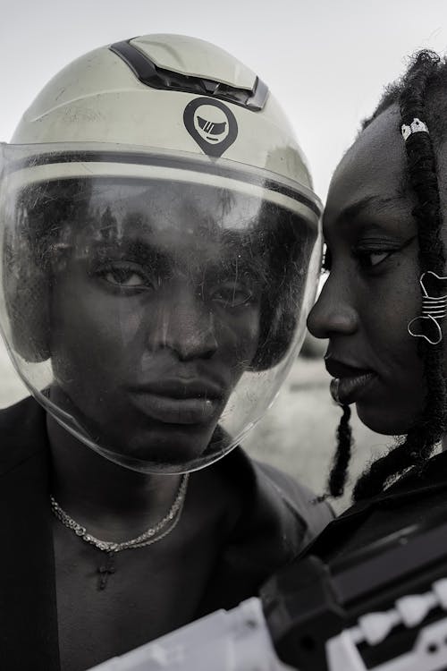 Black and white of African American male wearing helmet on head and transparent shield on face with black woman