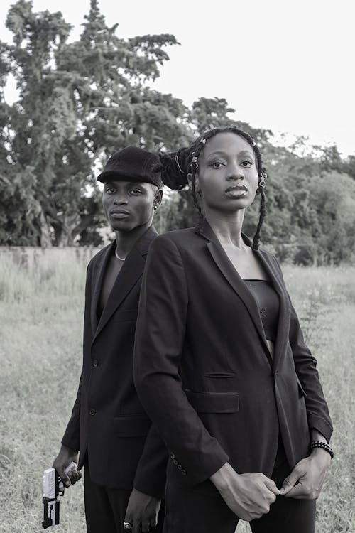 Man and Woman Wearing Coats Standing on Green Grass Field