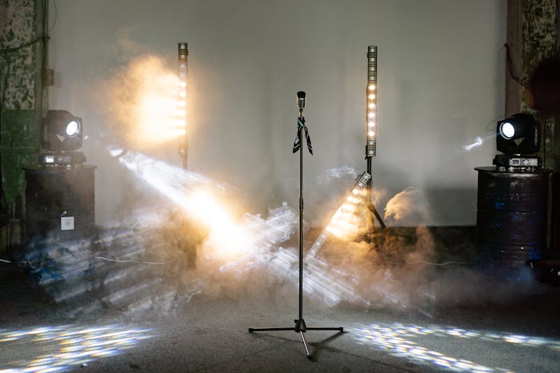 Microphone on stage surrounded by dramatic lights and smoke
