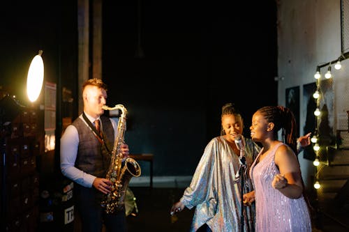 A Man Playing the Saxophone and Women Singing Together