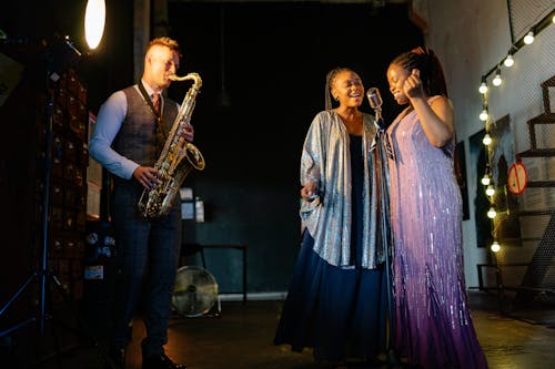 A Pair of Singers Singing with a Man Playing the Saxophone