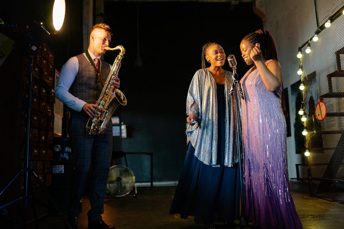 Free A Pair of Singers Singing with a Man Playing the Saxophone Stock Photo
