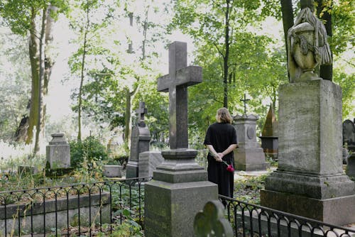 A Woman With Flowers Standing at a Cemetery 