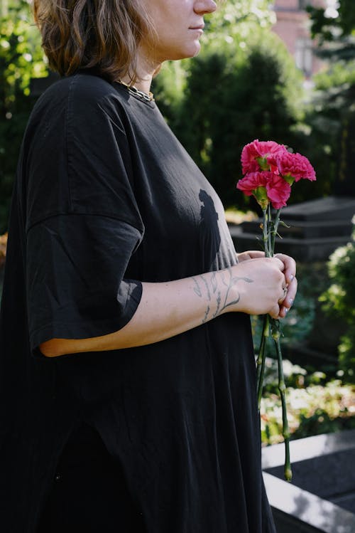 A Woman in Black Shirt Holding Pink Flowers with Long Stems