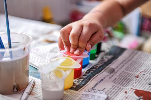 Free Close-up of a child's hand engaged in finger painting with colorful paints. Stock Photo