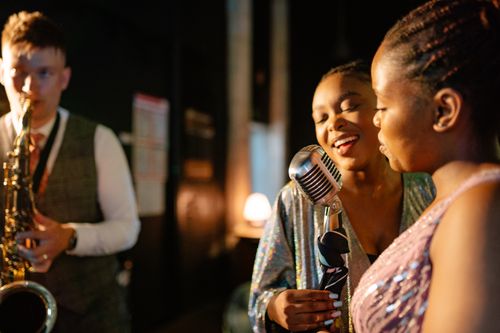Free Energetic concert featuring performers with microphones and saxophonist on stage. Stock Photo