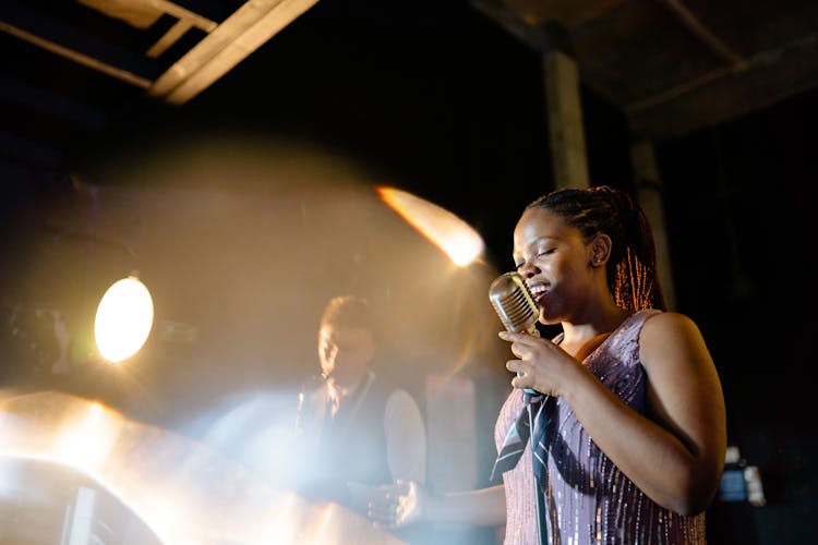 Woman In Pink Sparkly Top Holding A Microphone Singing