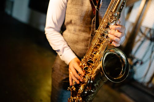 Person in White Long Sleeve Shirt Playing a Saxophone