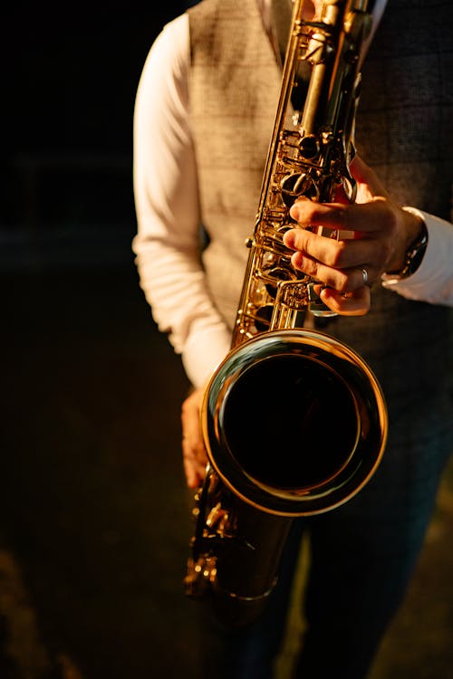 A Person in White Long Sleeve Shirt Playing Saxophone