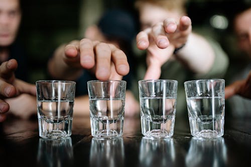 Shot Glasses With Clear Liquid on a Black Surface