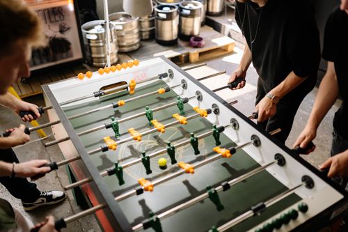 Free Energetic scene of people playing foosball indoors with vibrant colors and dynamic movement. Stock Photo