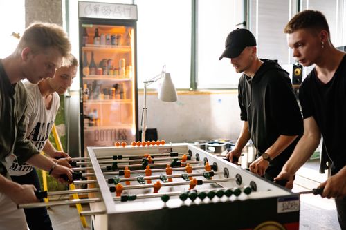 Free Four young men playing foosball in a lively indoor setting, showcasing camaraderie and fun. Stock Photo