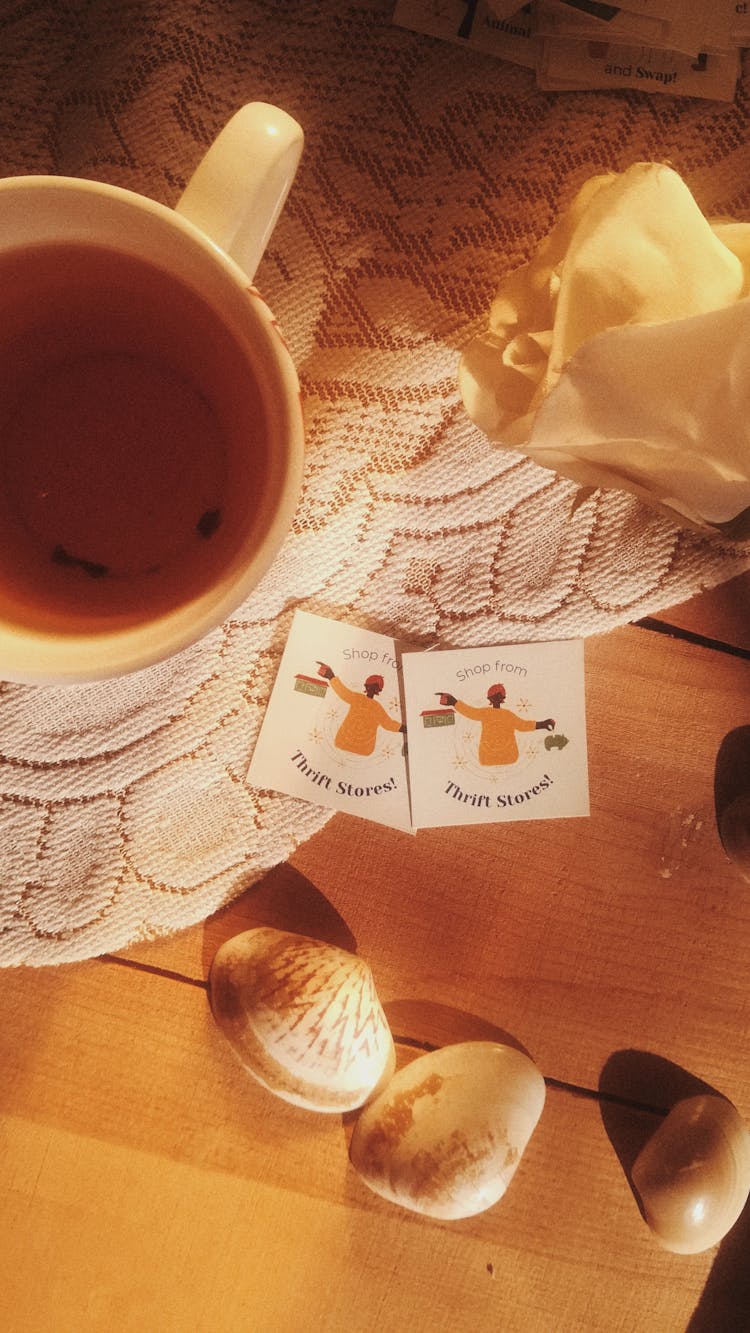 A Pair Of Thrift Stores Stickers On A White Table Mat Beside A Cup Of Tea