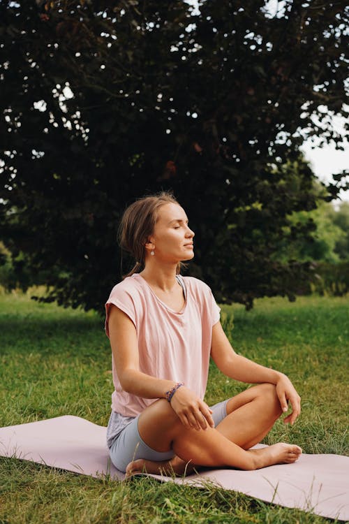 Free Photo of a Woman in a Pink Shirt Meditating with Her Eyes Closed Stock Photo