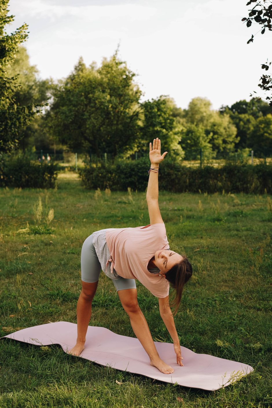 Woman practicing yoga on a mat in a green park