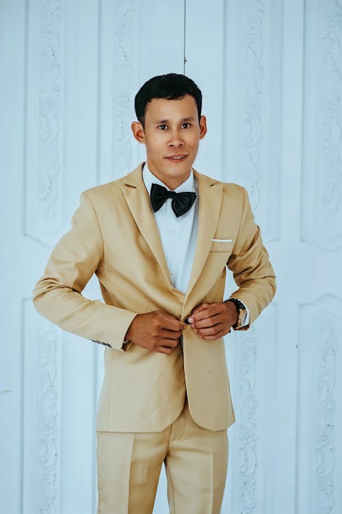 Free Man in Golden Suit Standing Near White Wall Stock Photo
