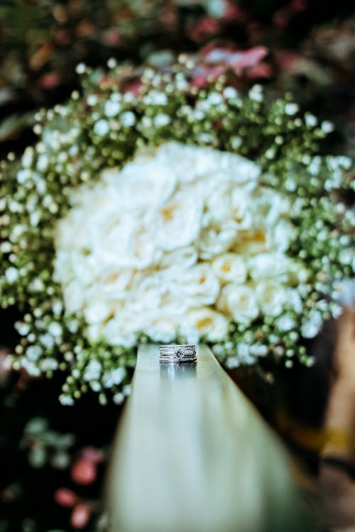 Free White Flower Bouquet Behind Engagement Ring on Banister Stock Photo