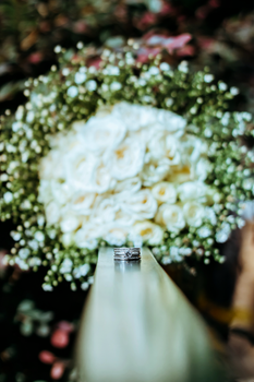Close-up of elegant wedding rings against a backdrop of romantic white roses and greenery.