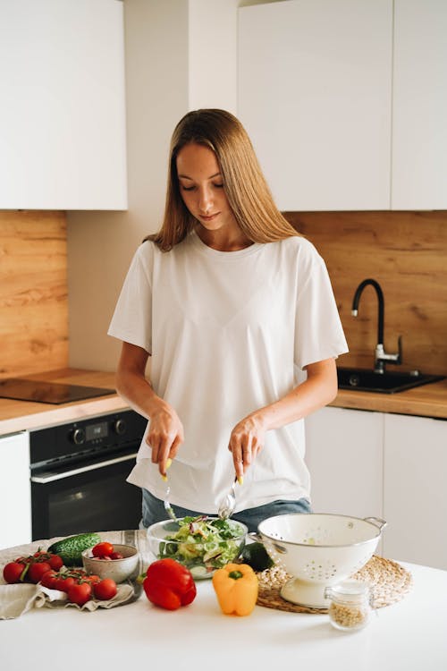 Woman in White T-shirt Holding Stirring Salad in Glass Bowl