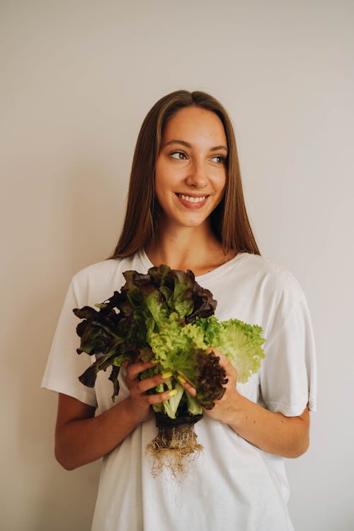 A Woman Smiling While Holding a Lettuce