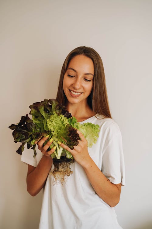 Woman in White Shirt Holding Green Vegetables